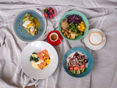 Hotel Böhlerstern: your conference hotel in Styria Variety of breakfast dishes with fruit, eggs, coffee, and yogurt on gray cloth