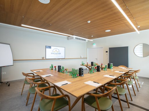 Böhlerstern: das Hotel in Kapfenberg für Seminare und Veranstaltungen Moderner Konferenzraum mit Holzstühlen, Tischen und Präsentationsbildschirm