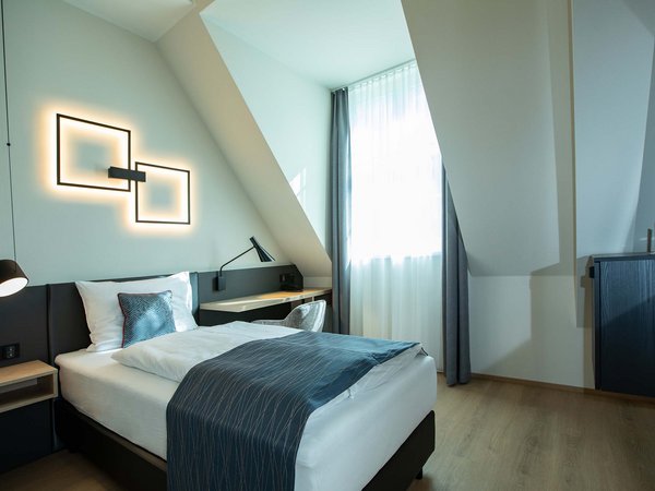 Böhlerstern: das Hotel in Kapfenberg für Seminare und Veranstaltungen Modernes Einzelzimmer mit Bett, Schreibtisch und dekorativer Wandbeleuchtung