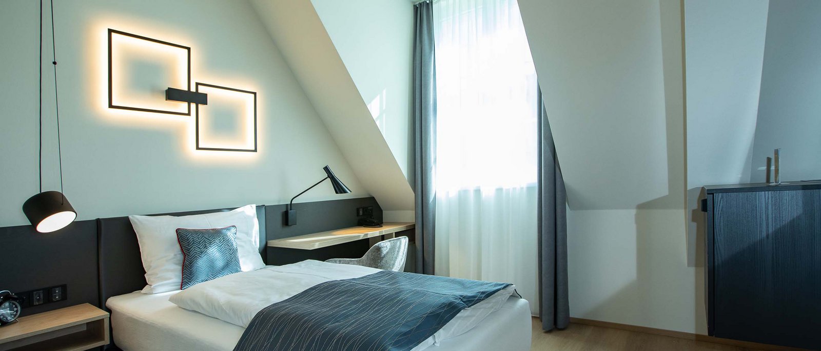 Single room Modern single room with bed, desk, and decorative wall lighting