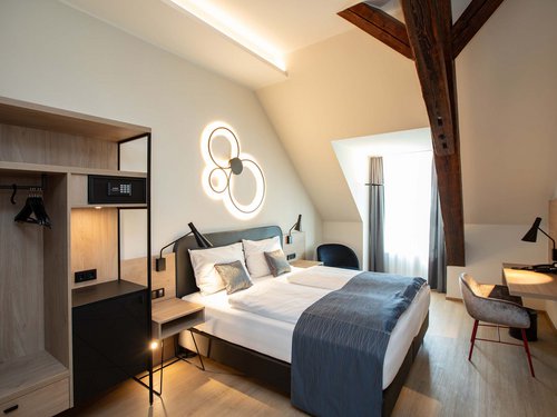 Single room Modern hotel room with double bed, desk, and wooden ceiling beams