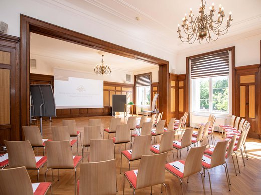 Böhlerstern: das Hotel in Kapfenberg für Seminare und Veranstaltungen Helles Seminarraum-Setup mit Stühlen, Tafel, Projektor und Kronleuchtern